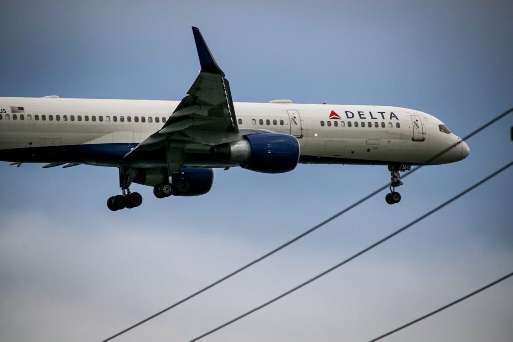 Delta Airlines Boeing 757 in flight against a clear blue sky.