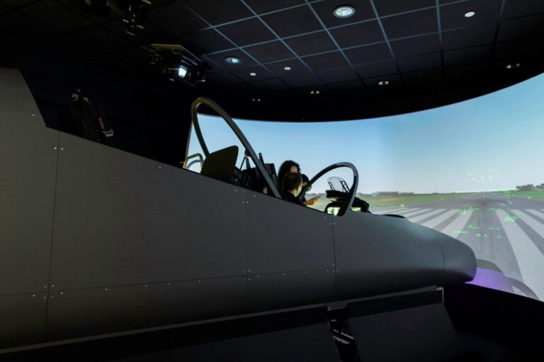 A student reviewing aircraft controls in a cockpit simulator