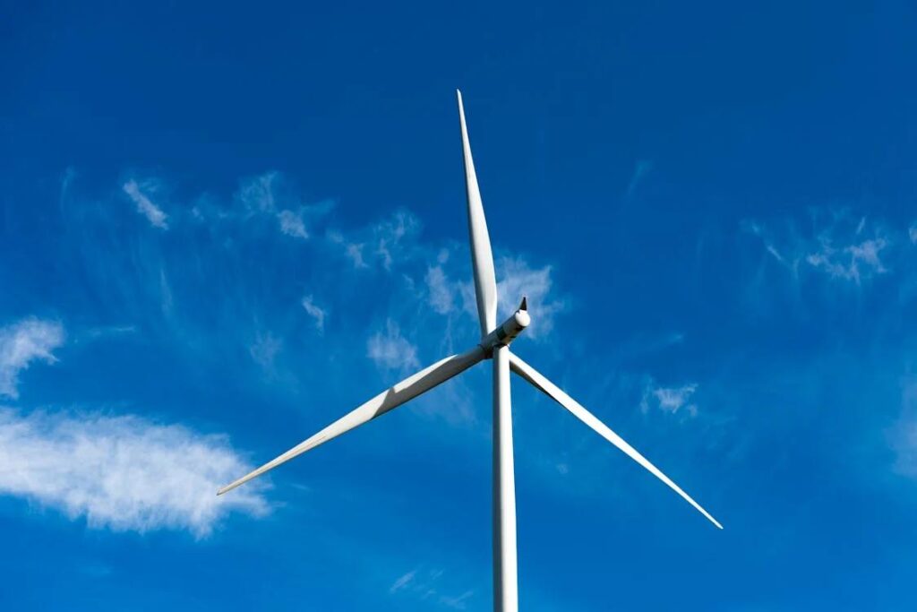Technician working on wind turbine blades against a clear sky
