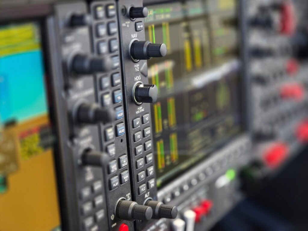 Detailed view of an aircraft cockpit instrument panel showcasing various control knobs and digital displays.