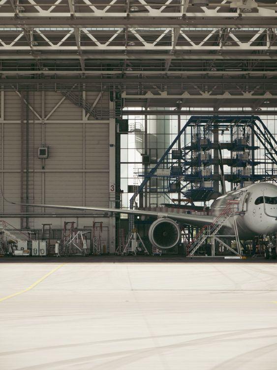 Aircraft maintenance technicians inspecting a commercial jet inside a modern maintenance hangar.