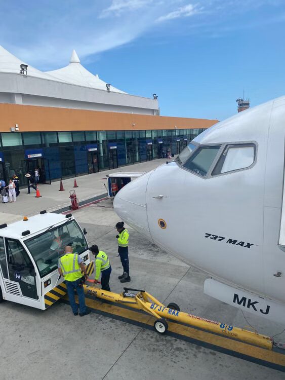 Boeing 737 parked on an airport apron with ground crew preparing the aircraft for service
